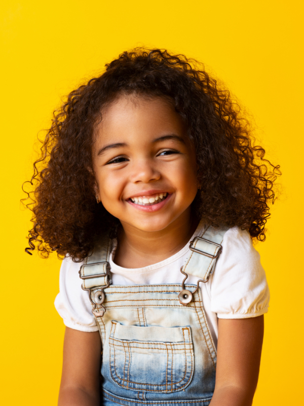 Happy smiling african-american child girl, yellow background